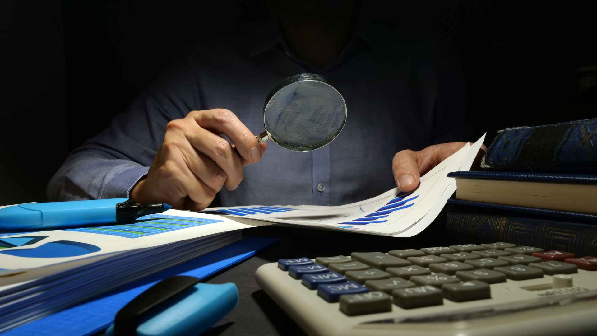 man sitting at a desk with a magnifying glass